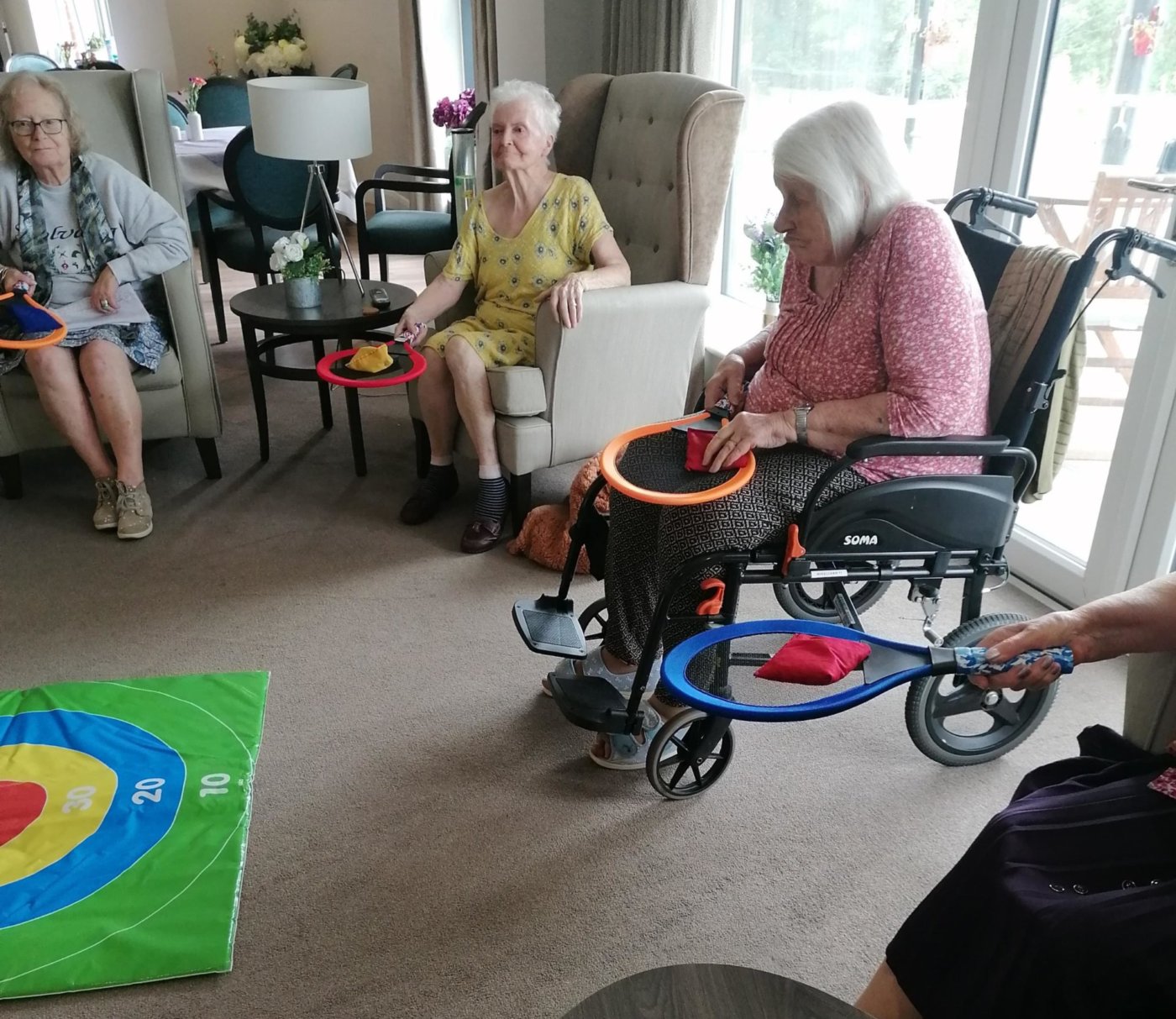 residents playing target tennis with bean bags and tennis racket and a target on the floor